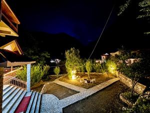 a backyard at night with a bench and lights at Tirthan Wood , a river view cottage in Banjār