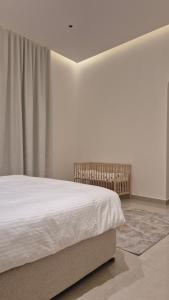 a white bedroom with a bed and a window at بيت الريف in Salalah