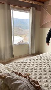 a bed in a room with a large window at Terrazas Jorge y Claudia in Bialet Massé
