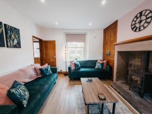 a living room with a green couch and a fireplace at Peak Cottage in Matlock