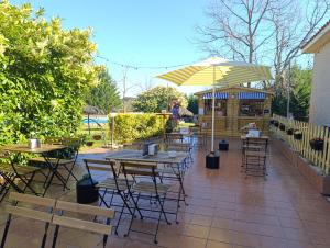 a patio with tables and chairs and an umbrella at Camping Arribes del Duero in Lumbrales