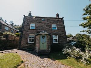 an old brick house with a green door at Peak Cottage in Matlock