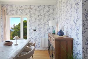 a dining room with a table and blue and white wallpaper at Marina House in Pechón