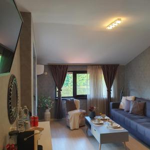 a living room with a blue couch and a table at Lake View Deluxe Tryavna БЕЗПЛАТНИ БАСЕЙН И ПАРКИНГ in Tryavna