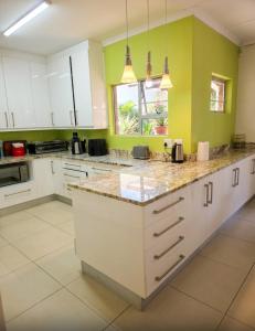 a kitchen with white cabinets and green walls at Blue Bend Valley in East London
