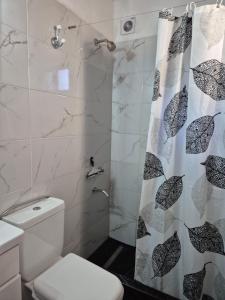 a bathroom with a shower with a toilet and a shower curtain at Casa Cris Pinamar in Pinamar
