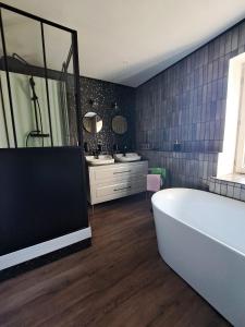 a bathroom with a bath tub and two sinks at La Ferme de Tréfumel in Tréfumel +31 photos
