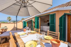 a dining table with an umbrella on a patio at Maison Blanche in Bordighera