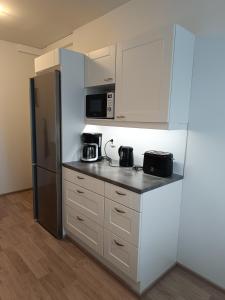 a kitchen with white cabinets and a refrigerator at Walhalla Kuhala apartment in Forssa