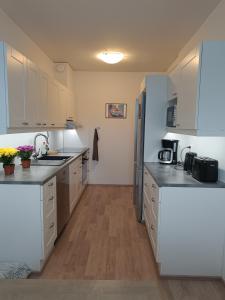 a kitchen with white appliances and wooden floors at Walhalla Kuhala apartment in Forssa
