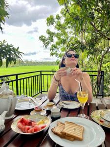 a woman sitting at a table with a glass of wine at Village Mango Resort Yala in Tissamaharama