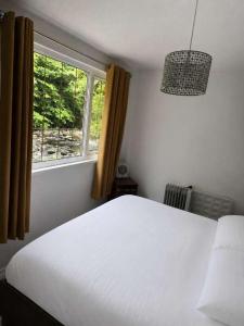 a bedroom with a white bed and a window at Waters Edge Lodge in Caeathro +21 photos