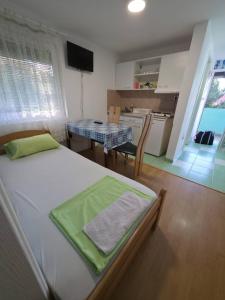 a bedroom with a bed and a table and a kitchen at Deskom Zelena Vila in Veliko Gradište