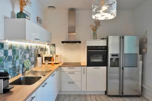 a kitchen with white cabinets and a stainless steel refrigerator at Ferienhaus Rafalenadjan, ideal für Familien, eigener Pool, schöne Terrasse, eigener Parkplatz by Riviera Homelife Management in Saint-Raphaël