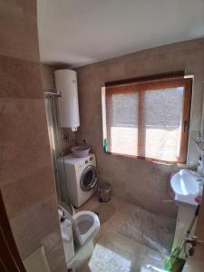 a bathroom with a toilet and a washing machine at Marina Bay in Kranevo