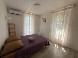 a bedroom with a bed with a purple blanket at La Maison Blanche in Perpignan