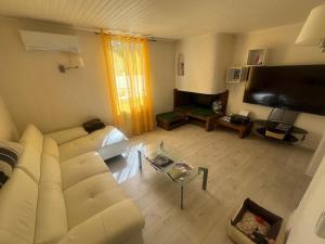 a living room with a white couch and a flat screen tv at La Maison Blanche in Perpignan