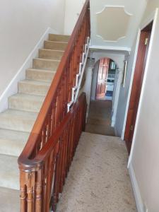 a staircase in a home with a wooden railing at Fortedward Farm House in Thurles