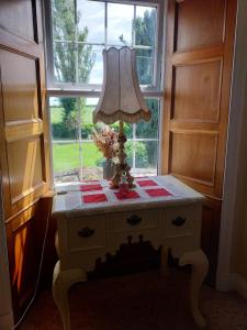 a table with a lamp on it in front of a window at Fortedward Farm House in Thurles