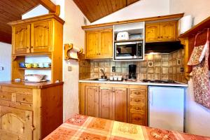 a kitchen with wooden cabinets and a white refrigerator at Les Toits des Cateaux in Combloux