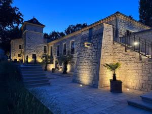 a large stone building with a clock tower at night at Bastide La Guilhabertie in Le Verdier