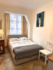 a bedroom with a bed and a window and a chair at Pottery Town Center Apartment in Bolesławiec