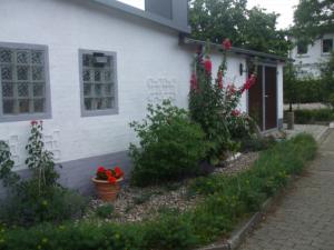 a white house with flowers in front of it at Ferienwohnung Lykos in Süderbrarup +4 photos