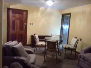 a living room with chairs and a table and a door at Downtown La Paz Apartment in Mojón de Achocalla