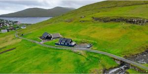 a house on top of a green hill with a road at Cabin by Gáansá in Sandavágur