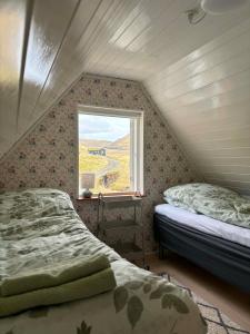 two beds in a room with a window at Cabin by Gáansá in Sandavágur