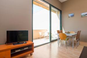 a living room with a television and a table with chairs at Costabravaforrent Pedró in L'Escala