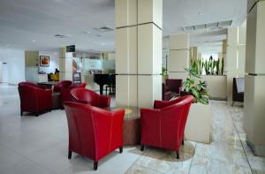 a waiting room with red chairs and a table at Alisa Hotel North Ridge in Accra +145 photos