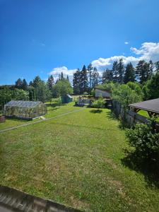 a large grassy yard with a greenhouse and trees at Privát ANAMON Gaštanová in Kežmarok