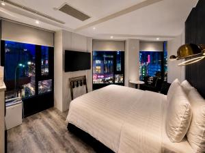 a bedroom with a large white bed and two windows at Hotel Relax III in Taipei