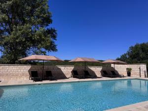 a swimming pool with chairs and umbrellas at Bastide La Guilhabertie in Le Verdier