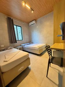 a room with two beds and a desk and a chair at Hotel Pousada da Praia in Recife