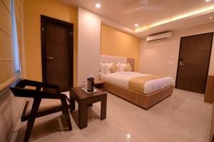 a bedroom with a bed and a chair and a table at Silver Pride Boutique Hotel in Jaipur