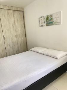 a bedroom with a bed with white sheets at Valparaiso in Valledupar
