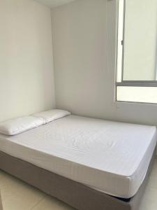 a bed in a white room with a window at Valparaiso in Valledupar