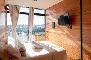a bedroom with a bed and a large window at Encantos de Altitude Cabanas e Studio Container in São Joaquim