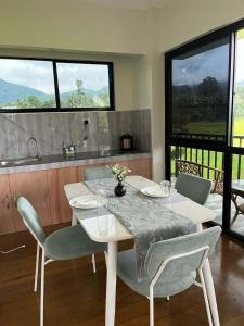 a dining room with a table and chairs and windows at Casa de Lilong in Mahinog