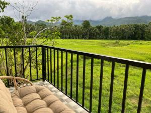 a balcony with a chair and a view of a field at Casa de Lilong in Mahinog