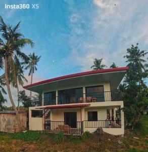 a house with a red roof and palm trees at Casa de Lilong in Mahinog +6 photos