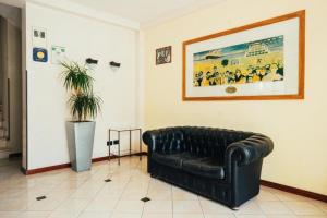 a black leather couch in a room with a painting at Arcangelo Meublè in Rimini