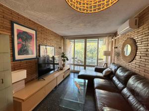 a living room with a leather couch and a television at HomeHolidaysRentals Miracel - Costa Barcelona in Malgrat de Mar
