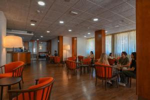 a group of people sitting at tables in a restaurant at Hotel Rialto in Grado