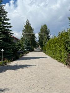 a cobblestone road with trees on both sides at Келечек in Cholpon-Ata