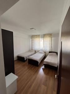 a room with two beds in a room with wooden floors at Келечек in Cholpon-Ata