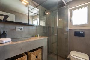 a bathroom with a glass shower and a sink at The Rock View Apartment in Mikonos +35 photos
