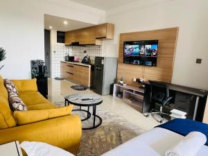 a living room with a yellow couch and a kitchen at Nyvin Homes at The Loftel in Ruaka